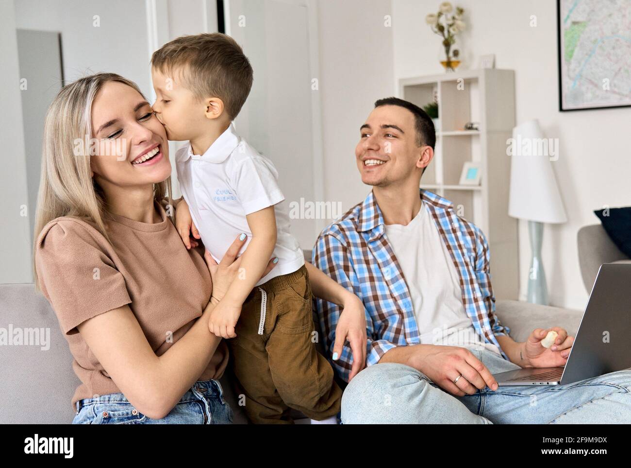 Cute toddler child son kissing dad on cheek having fun at home. Stock Photo