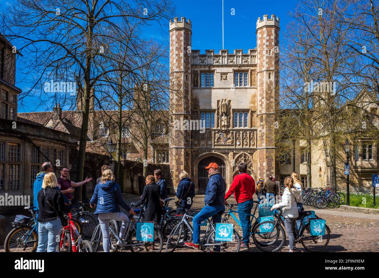Cambridge Bike Tours tourists pause in front of the C16th Trinity College Great Gate with a guide. Cambridge Cycle Tours. Stock Photo