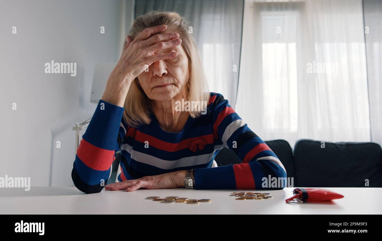 Worried old woman running out of money. Counting coins on the table. High quality photo Stock Photo