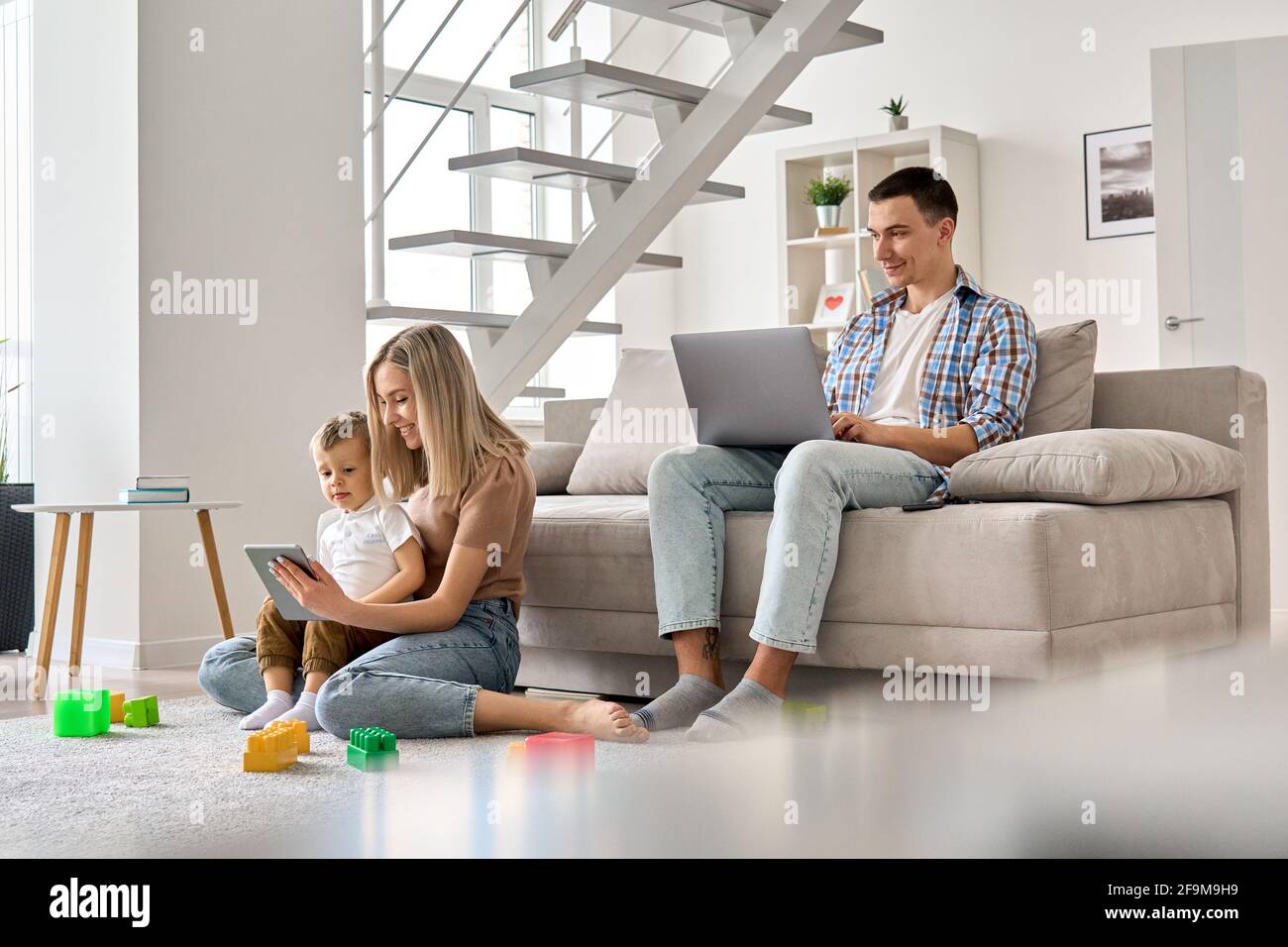 Happy family mom, dad and child son using laptop and digital tablet at home. Stock Photo