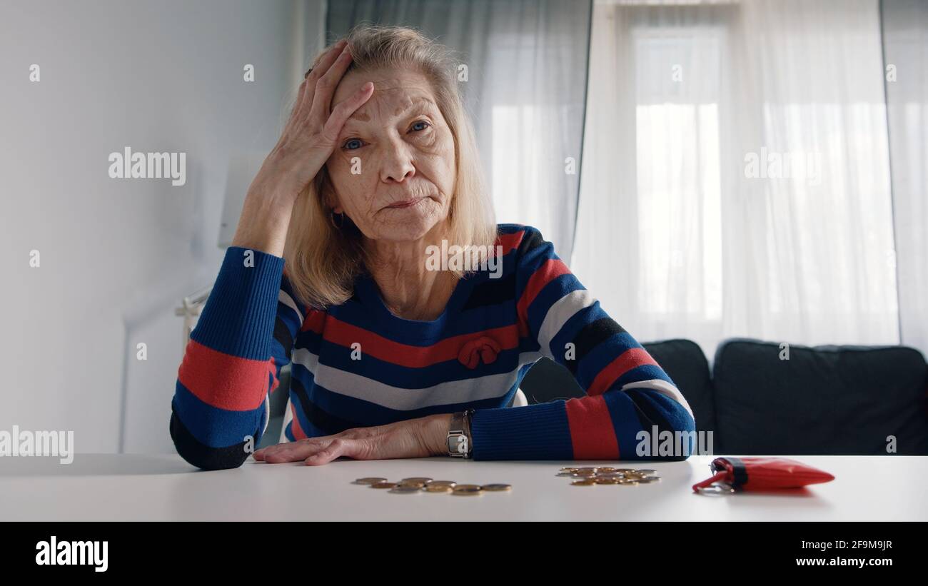 Worried old woman running out of money. Counting coins on the table. High quality photo Stock Photo