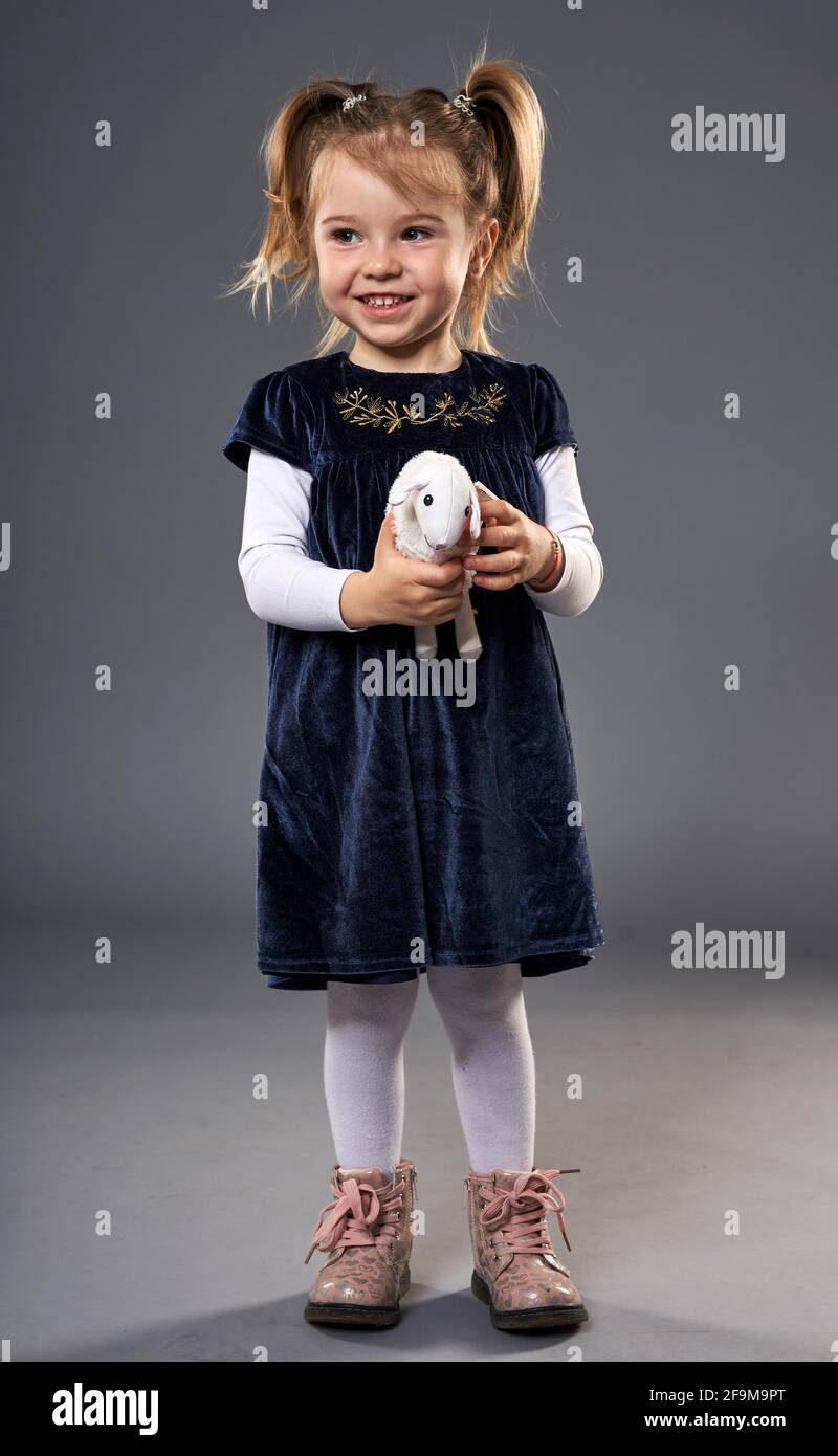 Adorable little blond girl with pigtails in deep blue dress and pink ...