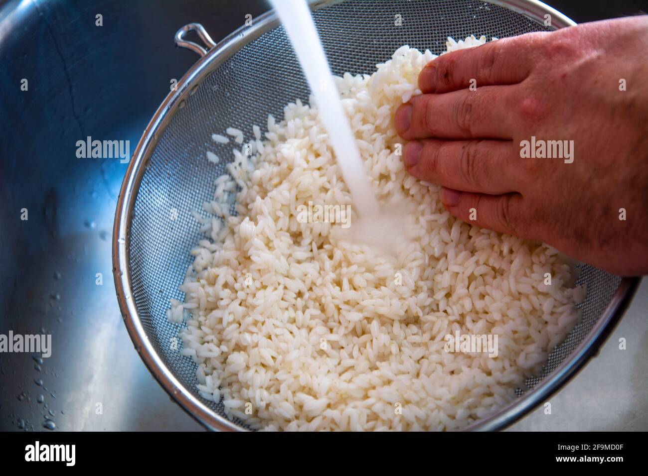 Washing the rice in the sieve in closeup Stock Photo Alamy