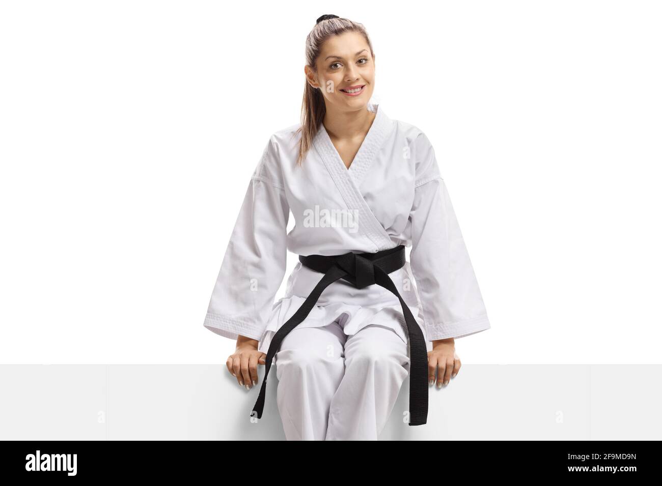 Woman in karate kimono and black belt sitting on a banner isolated on white  background Stock Photo - Alamy
