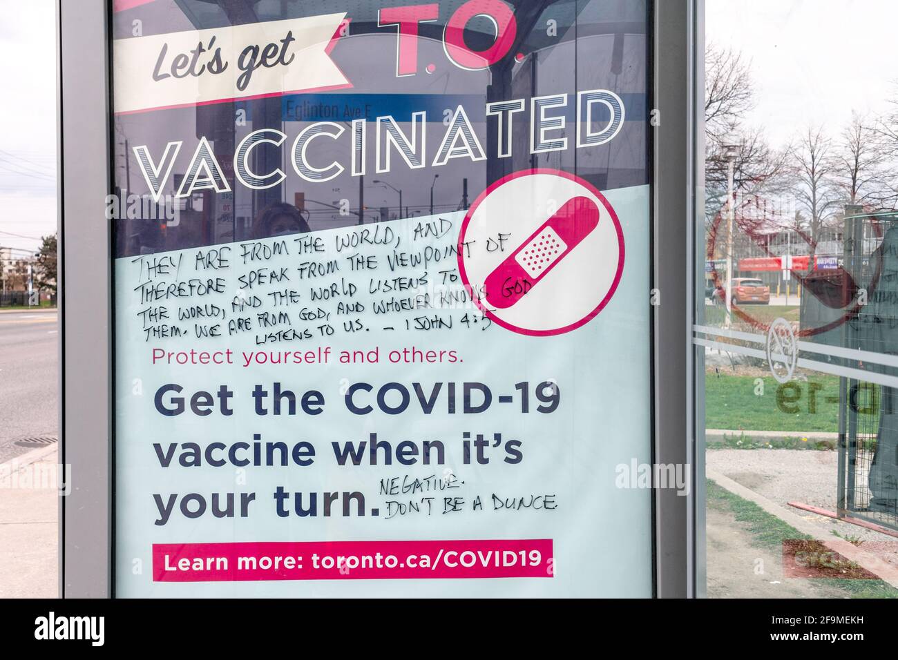 Covid-19 vaccination campaign sign vandalized with Christian scripture promoting the exact opposite. It is seen on a TTC (Toronto Transit Commission) Stock Photo