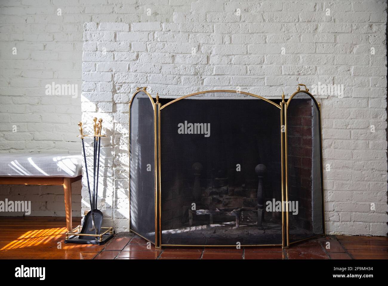 Fireplace with black fire guard screen and tools like shovel and poker