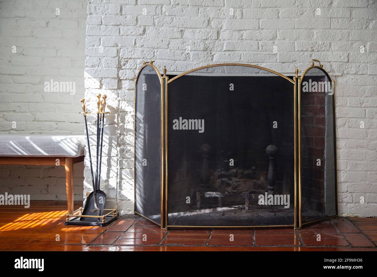 Fireplace with black fire guard screen and tools like shovel and poker