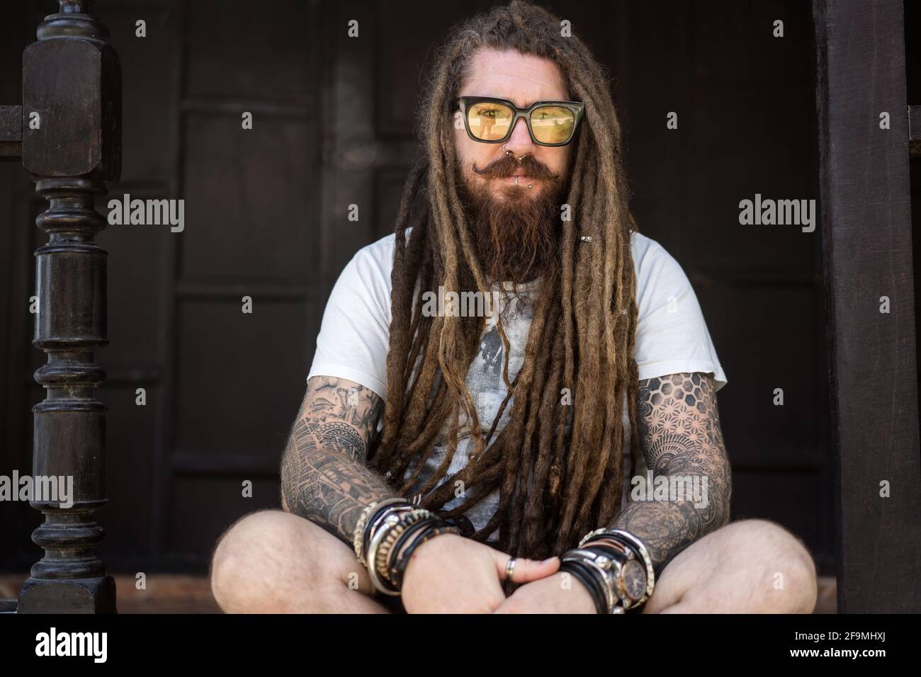 hipster guy with dreadlocks and tattoo sitting on the beach in thailan Stock Photo - Alamy