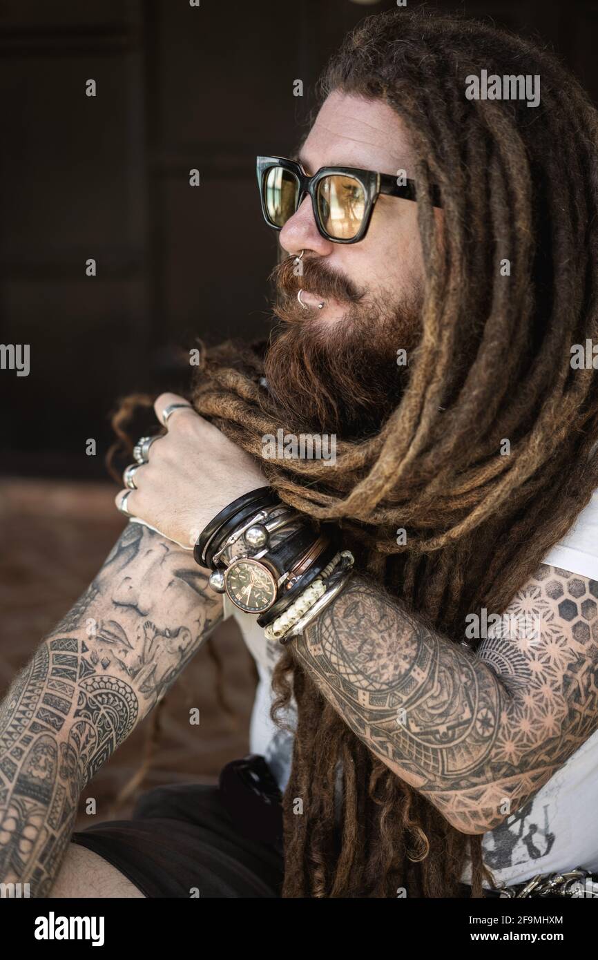 hipster guy with dreadlocks and tattoo sitting on the beach in thailan Stock Photo - Alamy