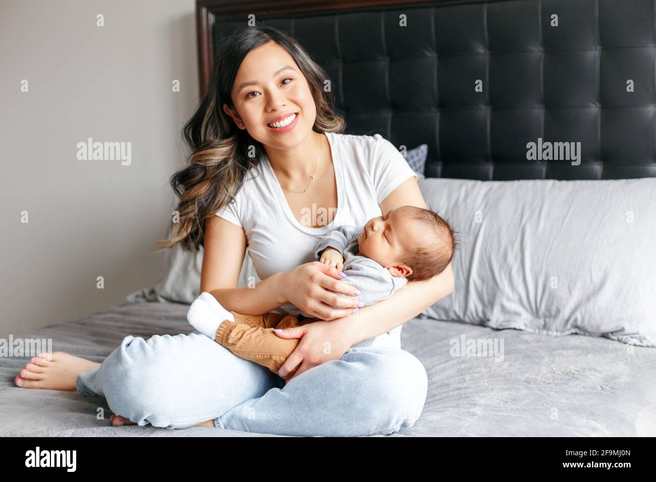 Mothers day holiday. Smiling Chinese Asian mother with newborn baby. Stock Photo