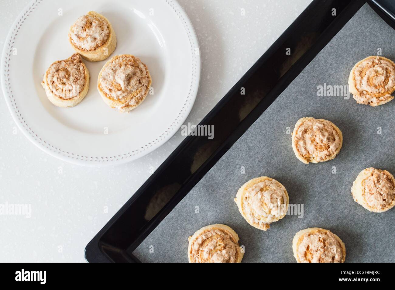 Cookies in white plate and black baking sheet on white counterto Stock Photo