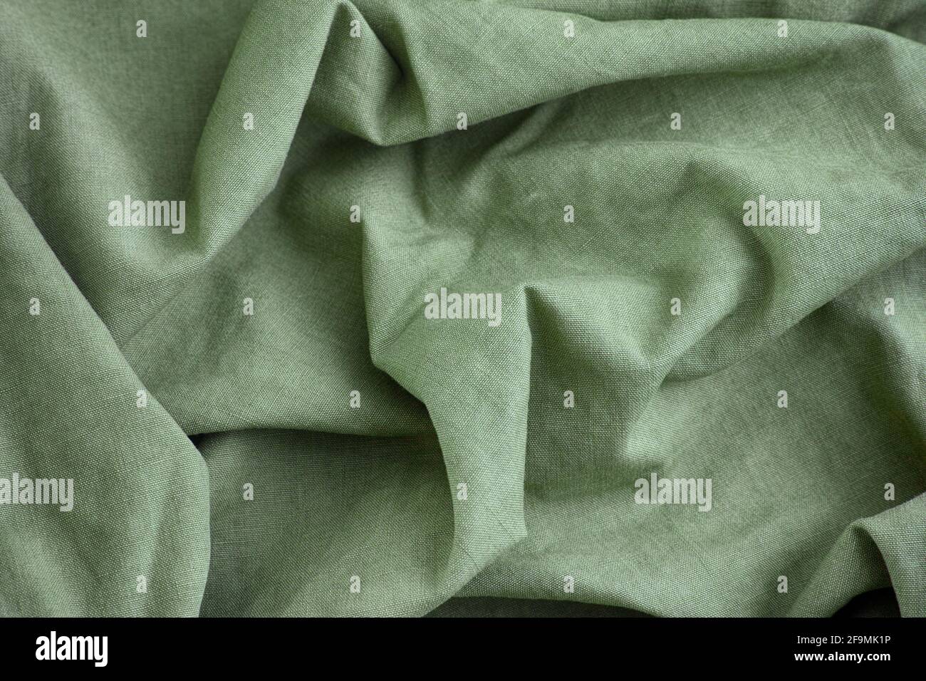Green crumpled fabric texture background. Close up. Stock Photo