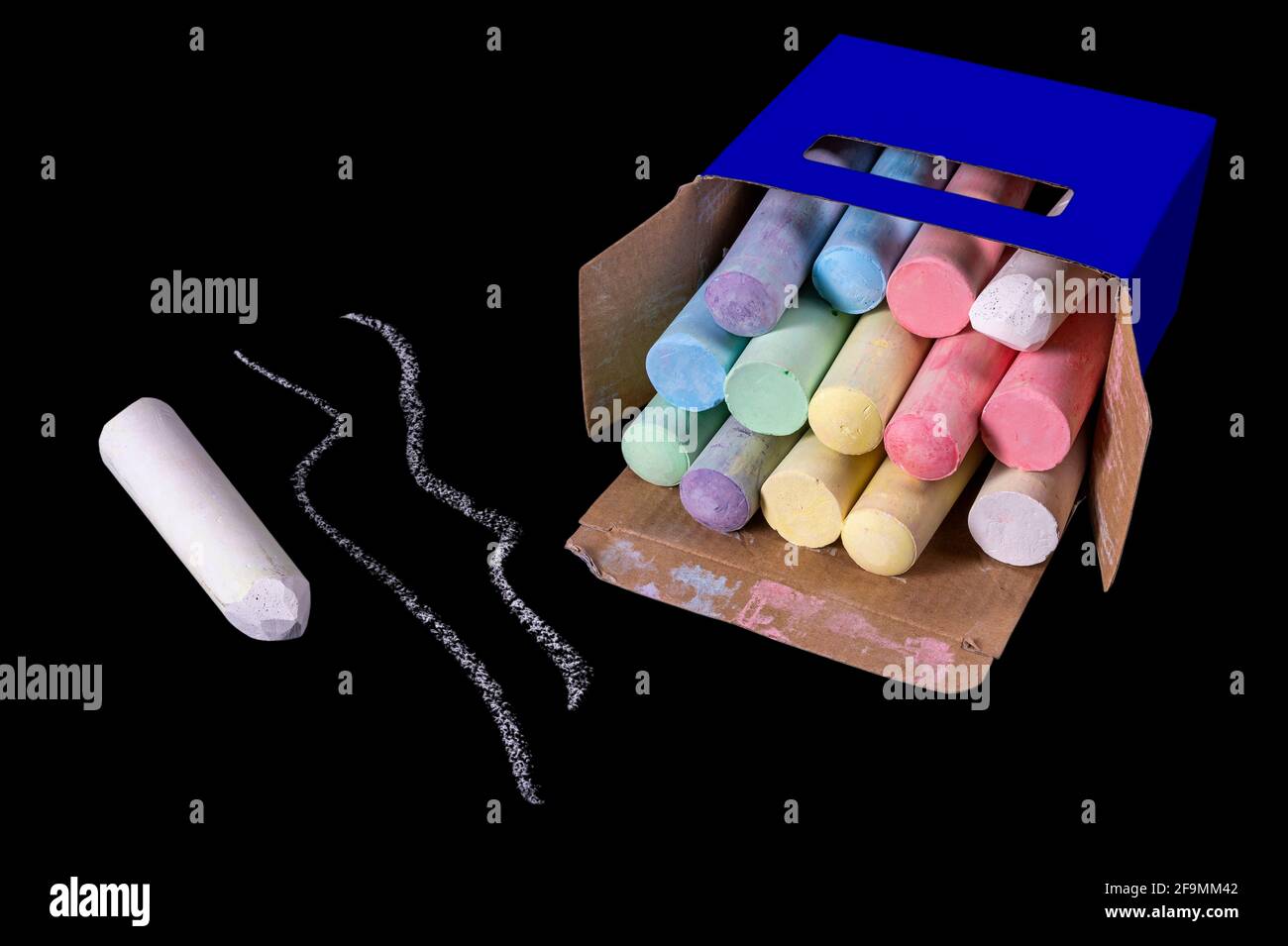 Chalk for drawing on the street in a cardboard box. Accessories for creative play for children. Dark background. Stock Photo