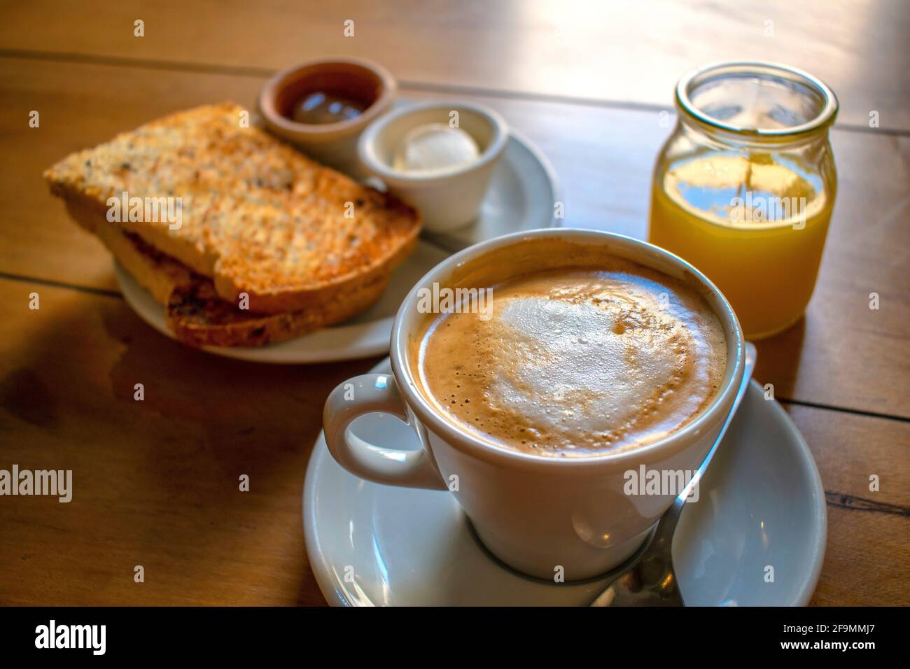 Coffee with milk with toast with cream cheese and jam, and orange juice