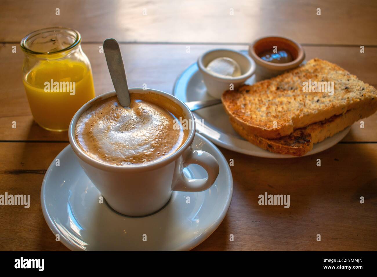 Coffee with milk with toast with cream cheese and jam, and orange juice