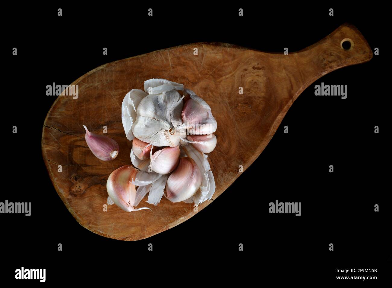 Image of garlic placed on cutting board studio isolated on dark background, view above Stock Photo
