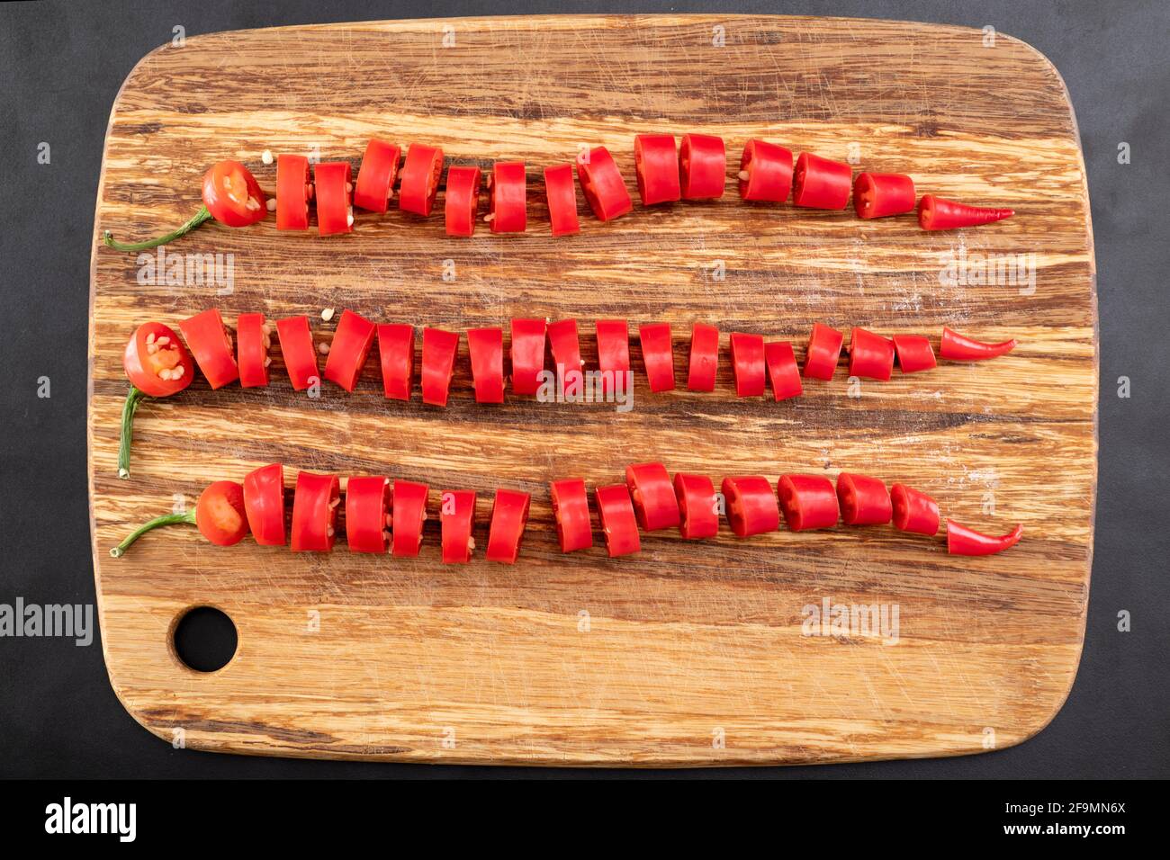 Cayenne, long red chili peppers sliced on cutting board Stock Photo