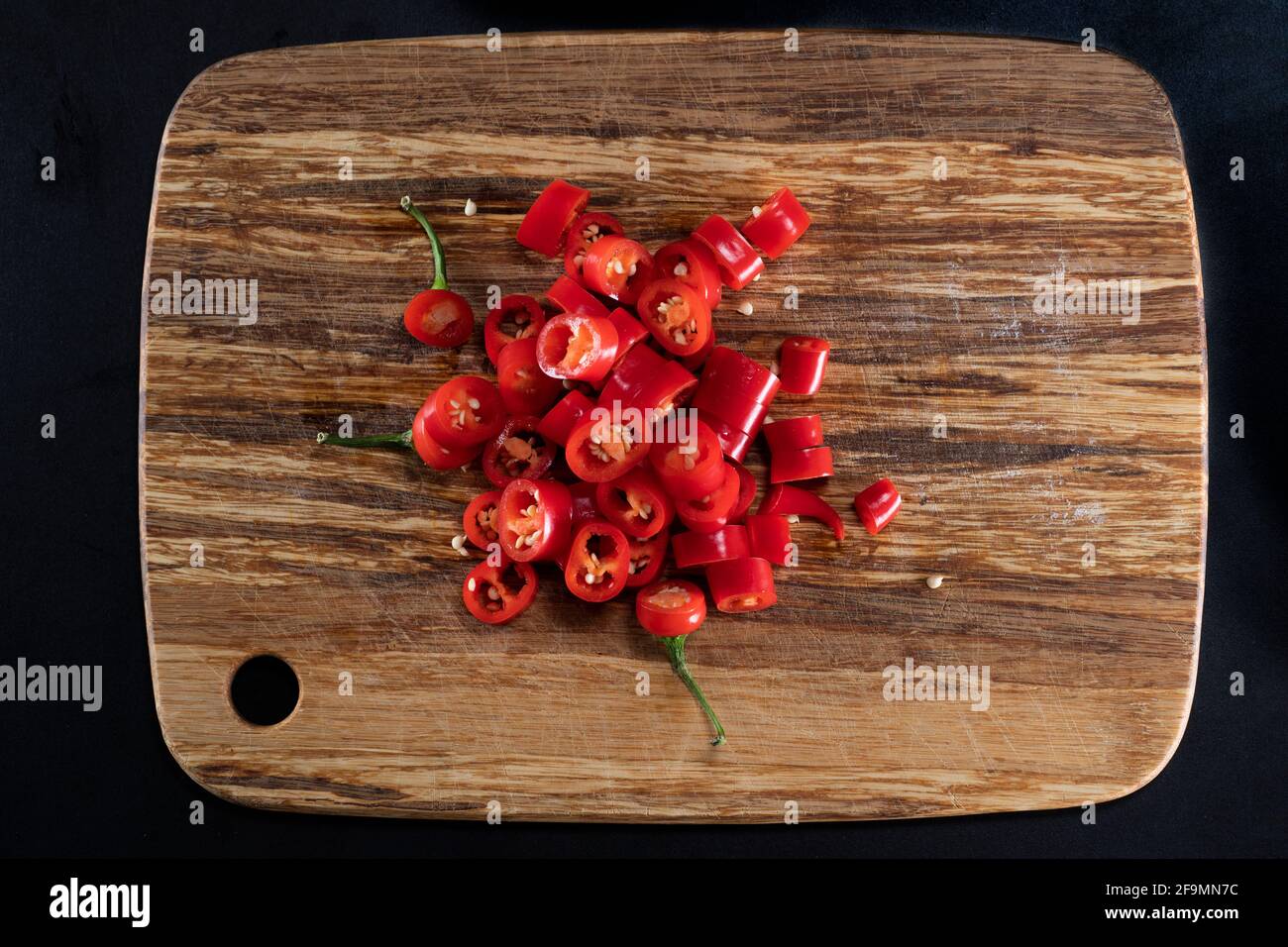 Cayenne, long red chili peppers on cutting board Stock Photo
