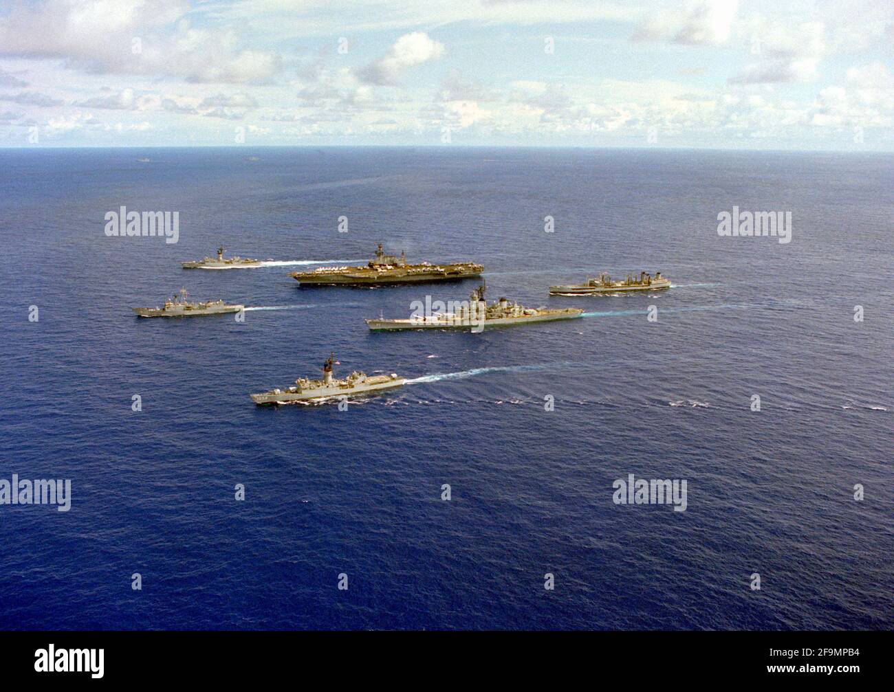 A port view of vessels in the aircraft carrier USS MIDWAY (CV-41) battle group underway in formation. The ships include, from left: the frigate USS MEYERKORD (FF-1058), and the guided missile frigate USS JOHN A. MOORE (FFG-19), front row; the battleship USS NEW JERSEY (BB-62), the aircraft carrier USS MIDWAY (CV-41) and the frigate USS FRANCIS HAMMOND (FF-1067), center, and the fleet oiler USNS MISPILLION (T-AO-105), rear Stock Photo