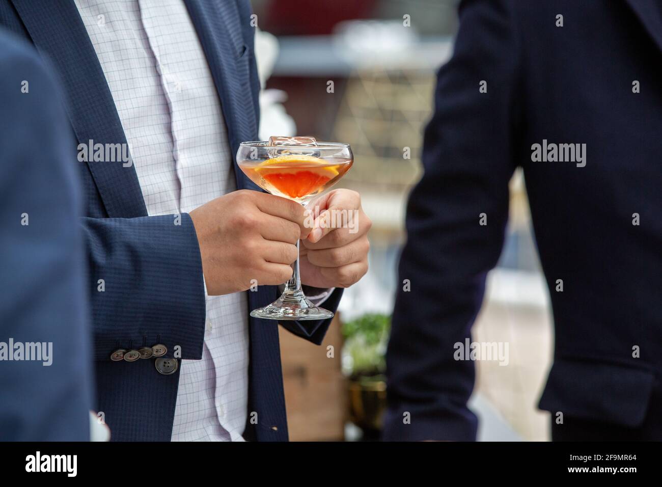 Man in suit holding a cocktail at a function Stock Photo