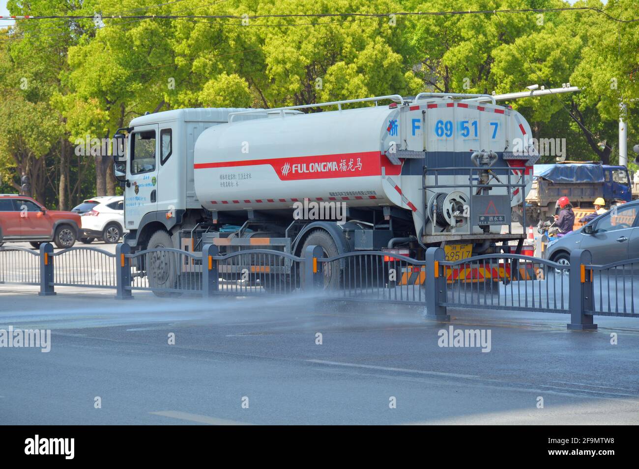 Water truck spraying a road in China, they are out daily to help keep dust levels down with the constant construction work going on. Stock Photo