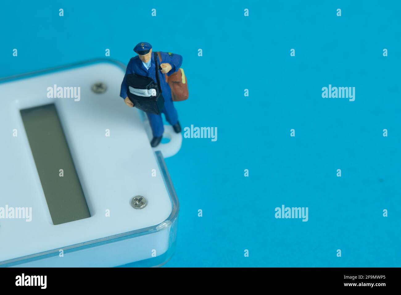 https://c8.alamy.com/comp/2F9MWP5/miniature-people-toys-conceptual-photography-calculate-parcel-package-weight-postman-courier-with-scale-isolated-on-blue-background-2F9MWP5.jpg