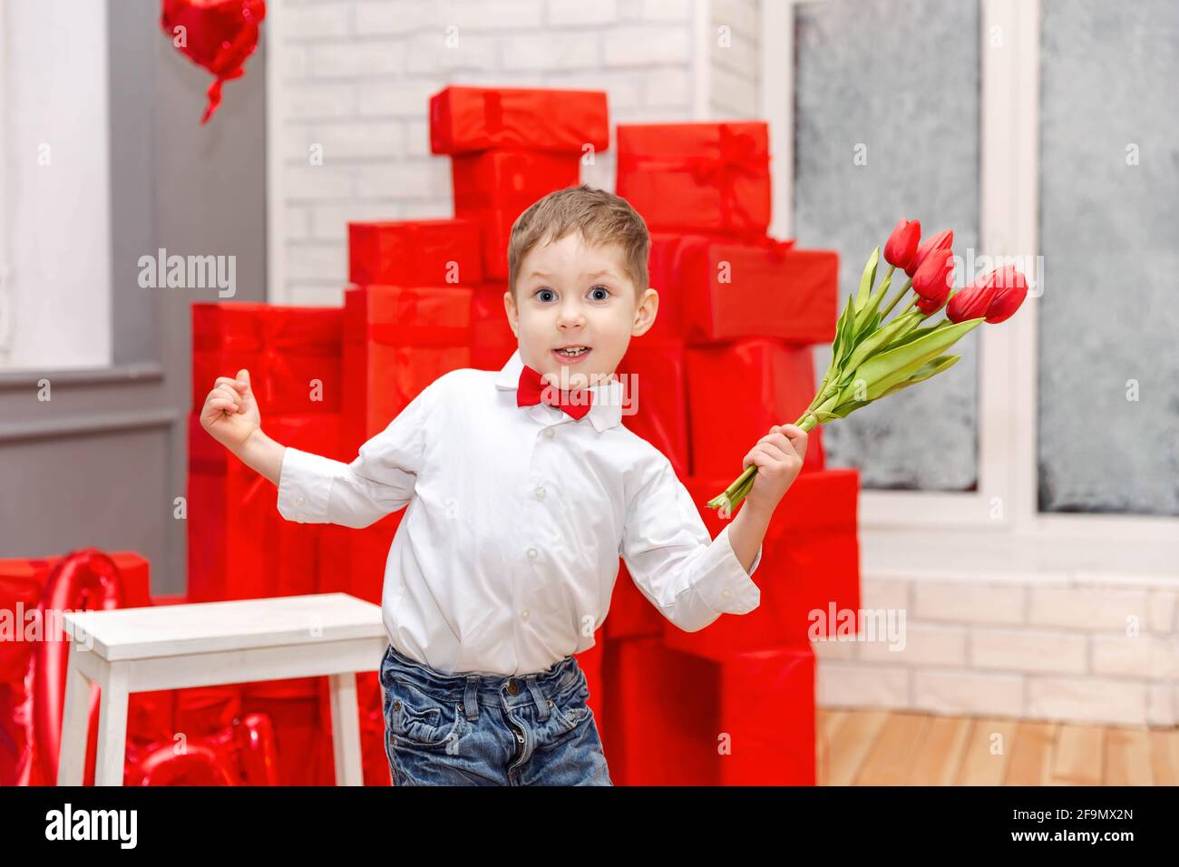 Funny kid congratulate mother on holiday and give flowers. Holidays Stock Photo
