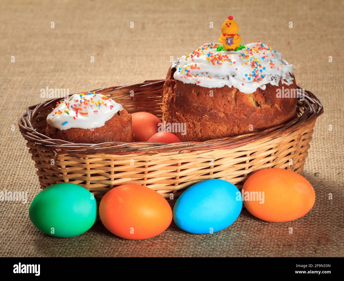 Easter cakes in wicker basket and colorful Easter eggs . Stock Photo