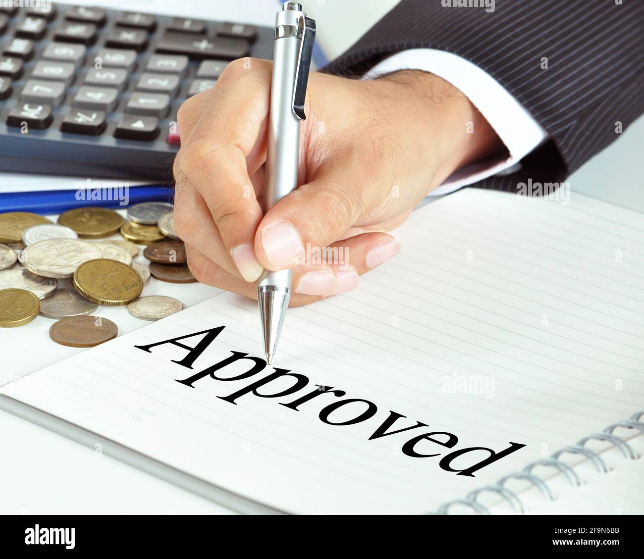 Hand with pen pointing to Approved word on the paper - financial & business abstract Stock Photo
