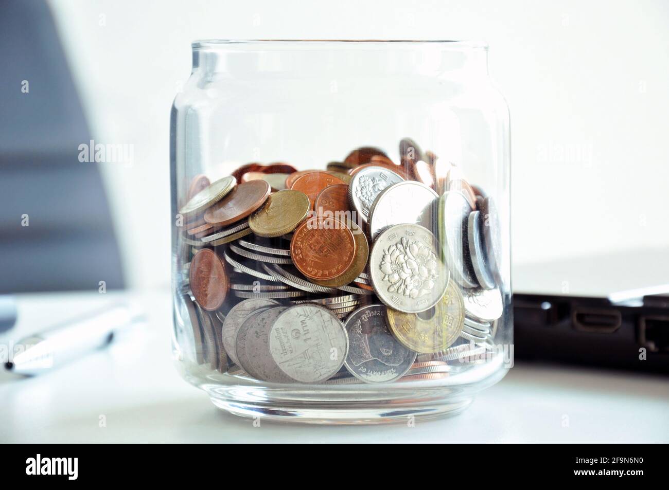 Coins in the glass jar - multi Asian currencies - saving concept Stock Photo