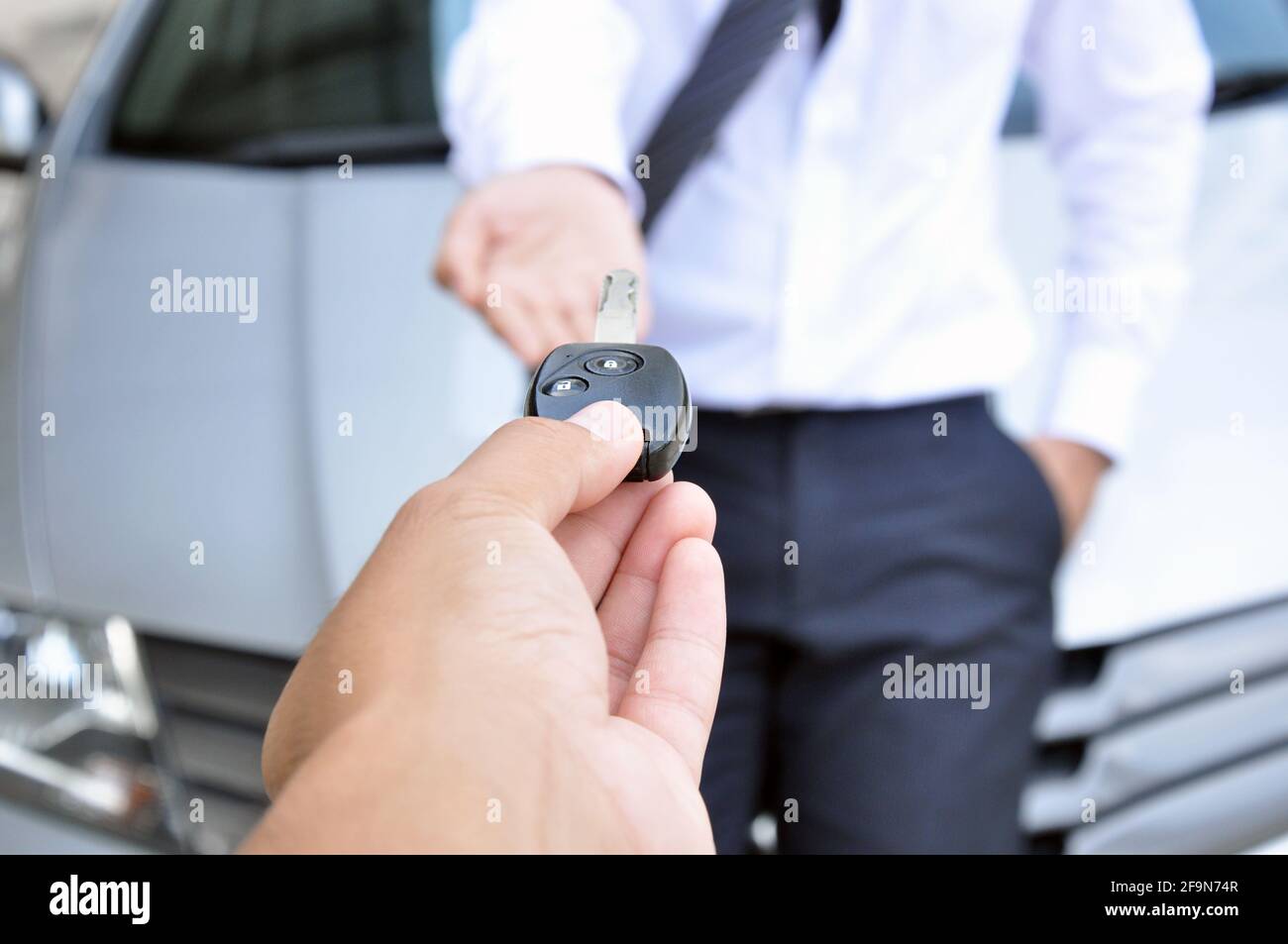 Hand giving a car key to another man car sale & rental service