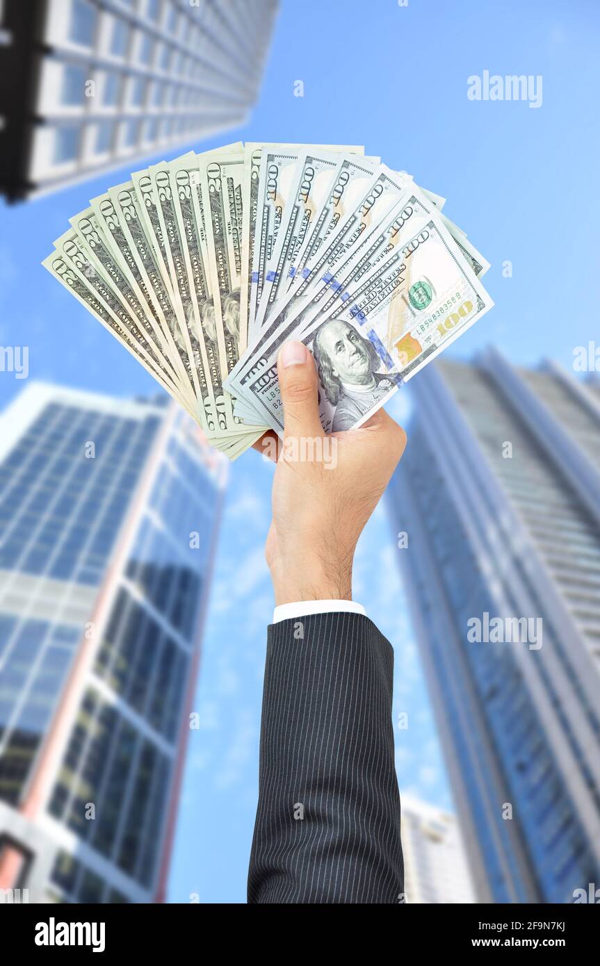 Hand holding money - United States Dollars (or USD) - on building background Stock Photo
