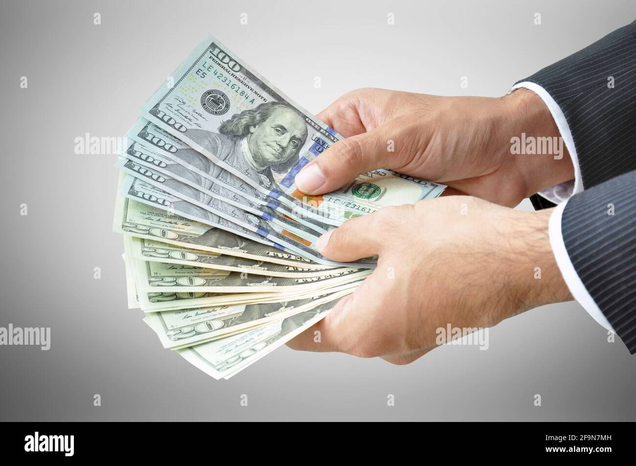 Money - hands holding banknotes (United States Dollars or USD) on gray background Stock Photo