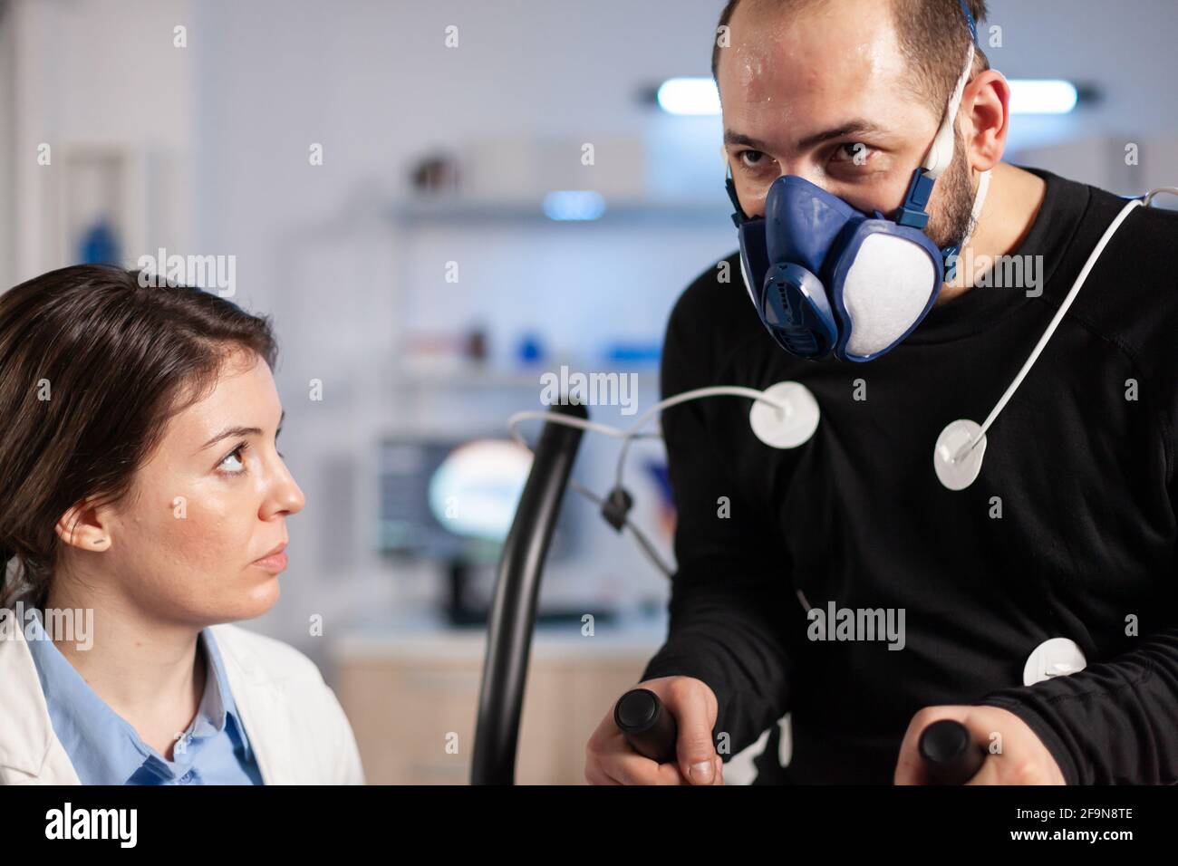 Sportman in science lab testing cardio performance, scientist analyzing training of athlete with