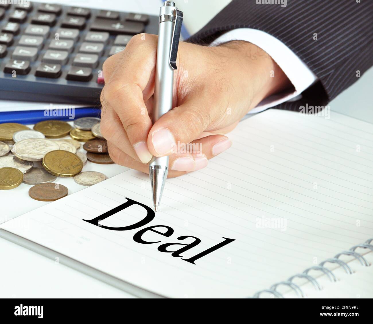 Businessman hand holding a pen pointing to Deal word on the paper - commercial & business concept Stock Photo