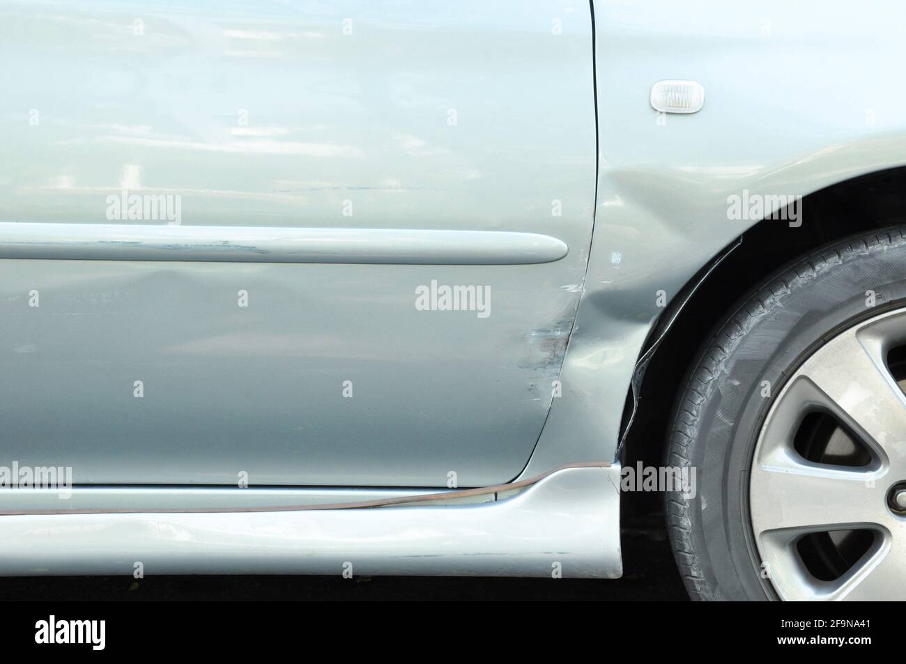 Damaged car with a dent near the wheel - can be considered as a fender bender Stock Photo