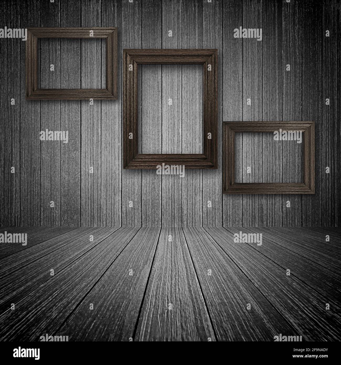Three wooden picture frames on the wall inside dark room Stock Photo