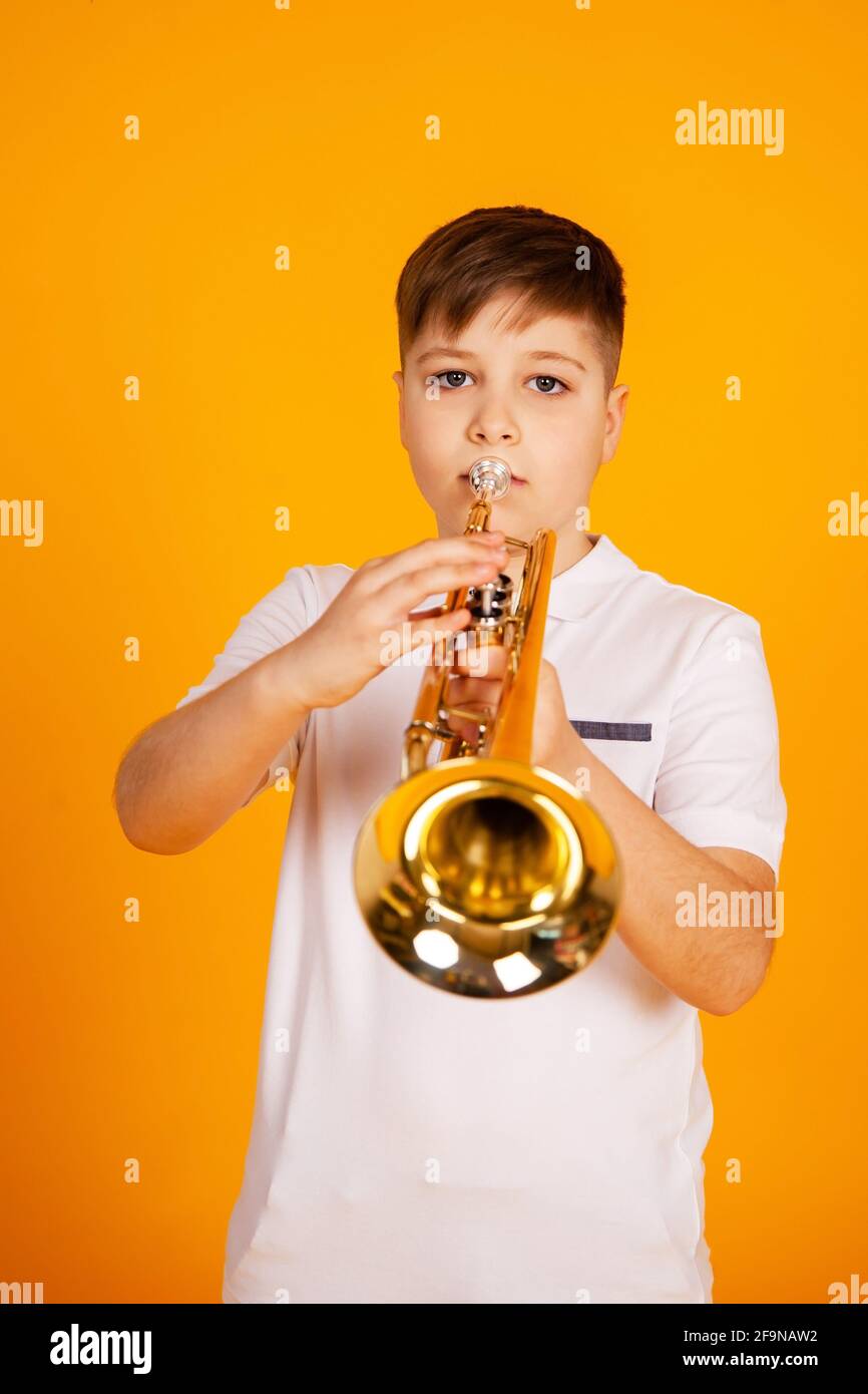 A boy plays the trumpet. Beautiful teenager boy plays trumpet musical