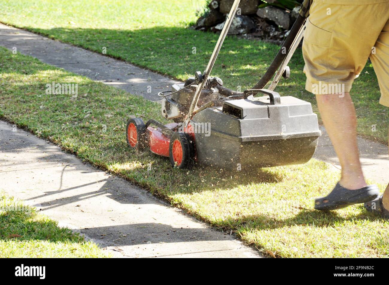 A man mowing lawn with lawn mower in the garden Stock Photo