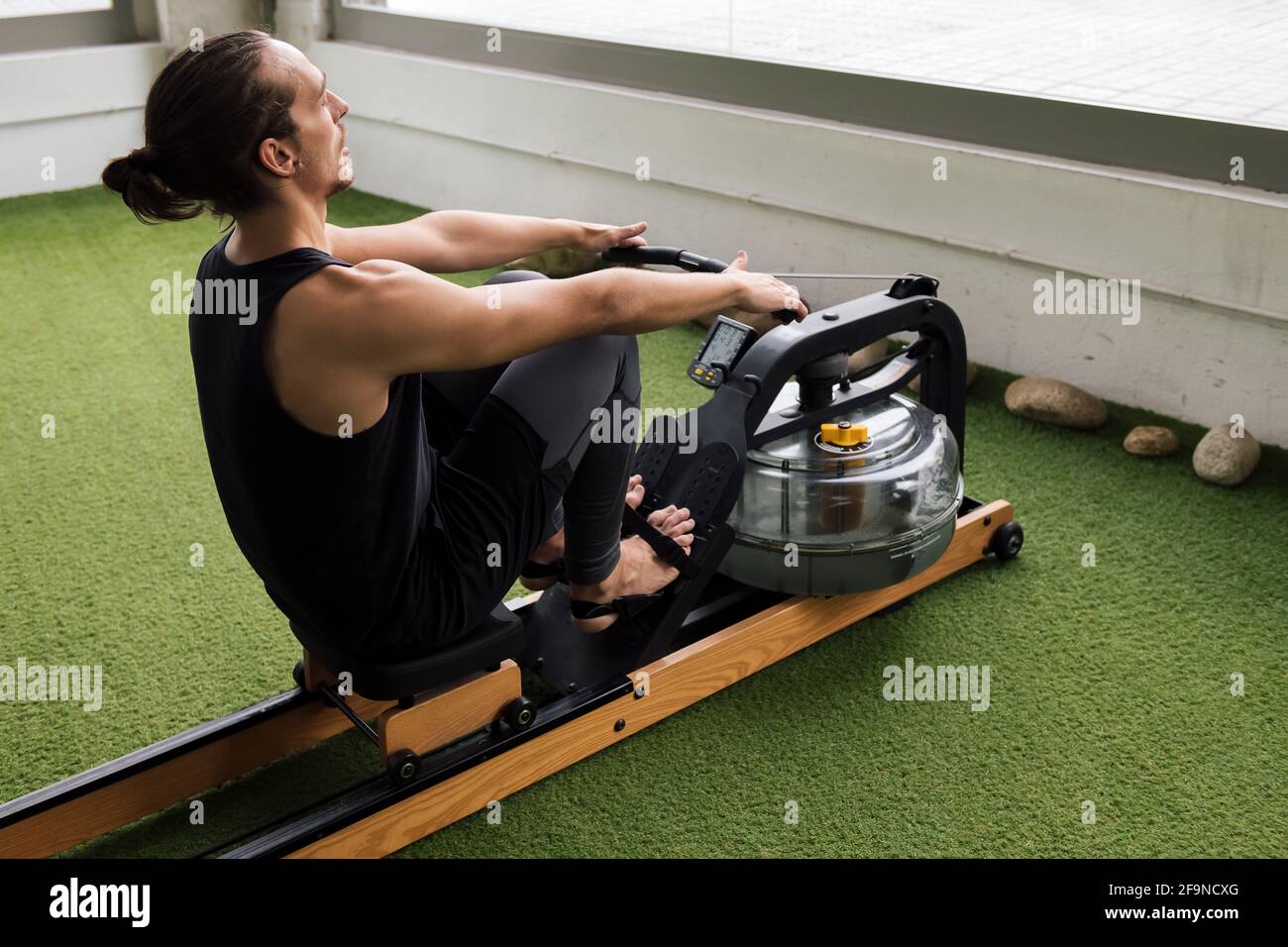 Water Rowing Trainer sportsman training in the gym on a water rowing machine, active and ...