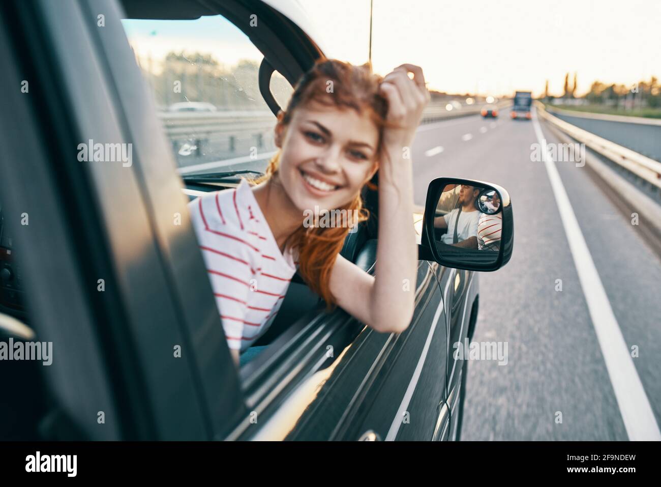 happy woman on the track peeking out of the car window in summer ...