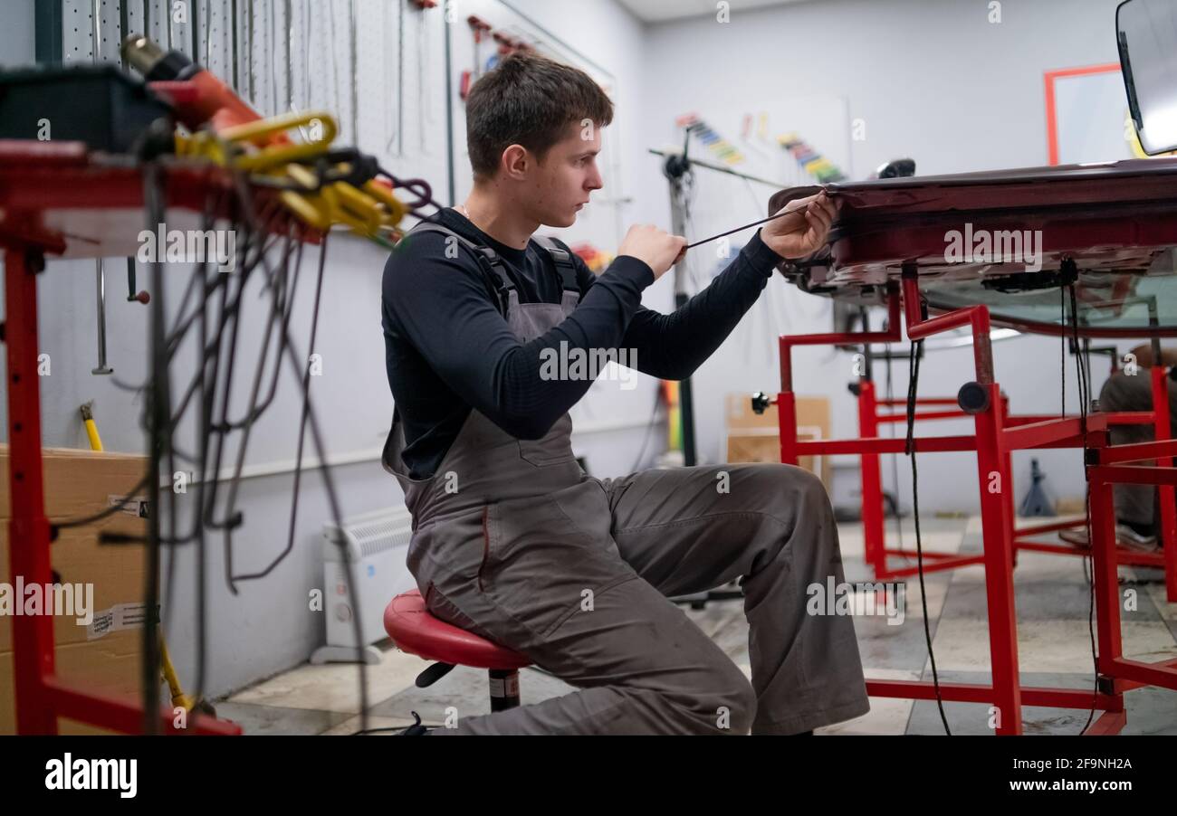 Dent removing work process of young professional car repair employer  Stock Photo