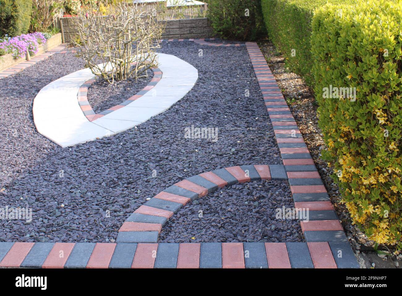 Low maintenance garden with coloured block edging and grey slate shingles. Garden hard landscaping services concept Stock Photo