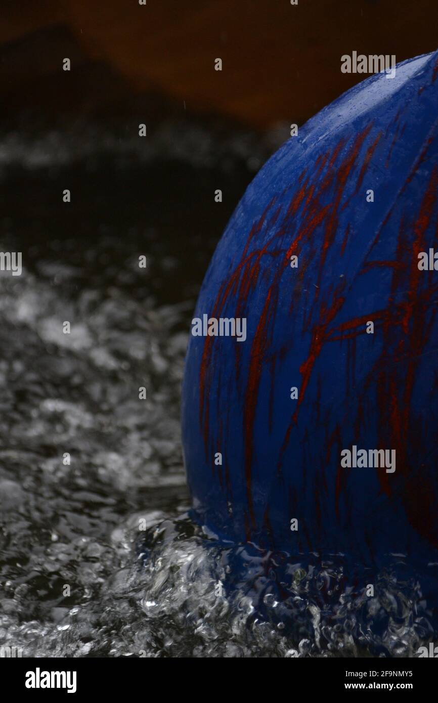 A blue fender or buoy with red markings, dragged through the water; bubbles making a wash or wake around it Stock Photo