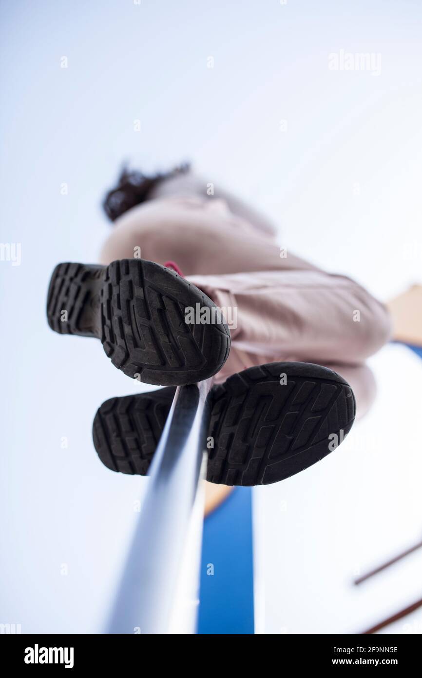 Child girl sliding down by fireman pole of playground. Low angle view Stock Photo