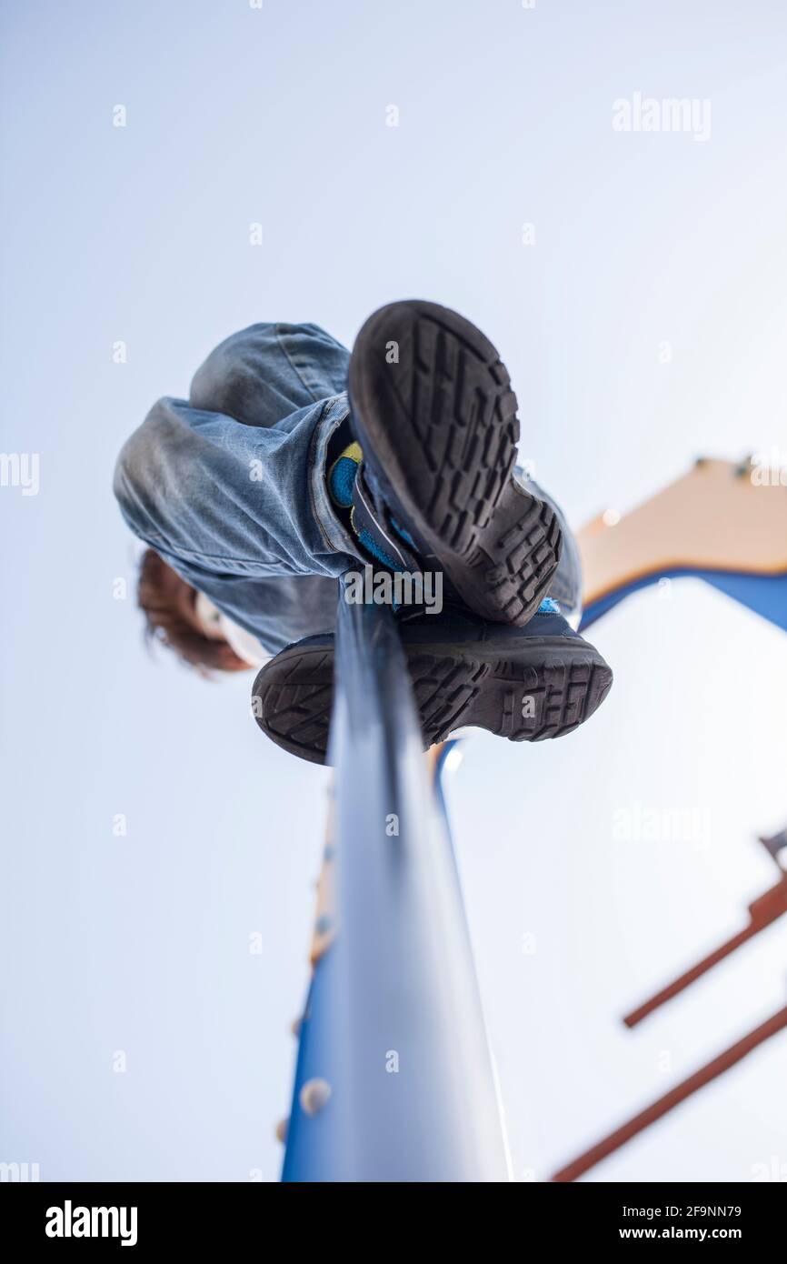 Child boy sliding down by fireman pole of playground. Low angle view Stock Photo