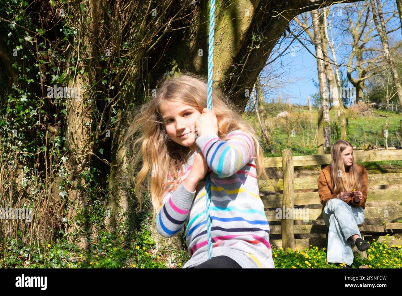 Young girl 8 yrs playing outside on garden swing in spring in the Welsh countryside after easing of Covid 19 restrictions in Wales UK KATHY DEWITT Stock Photo