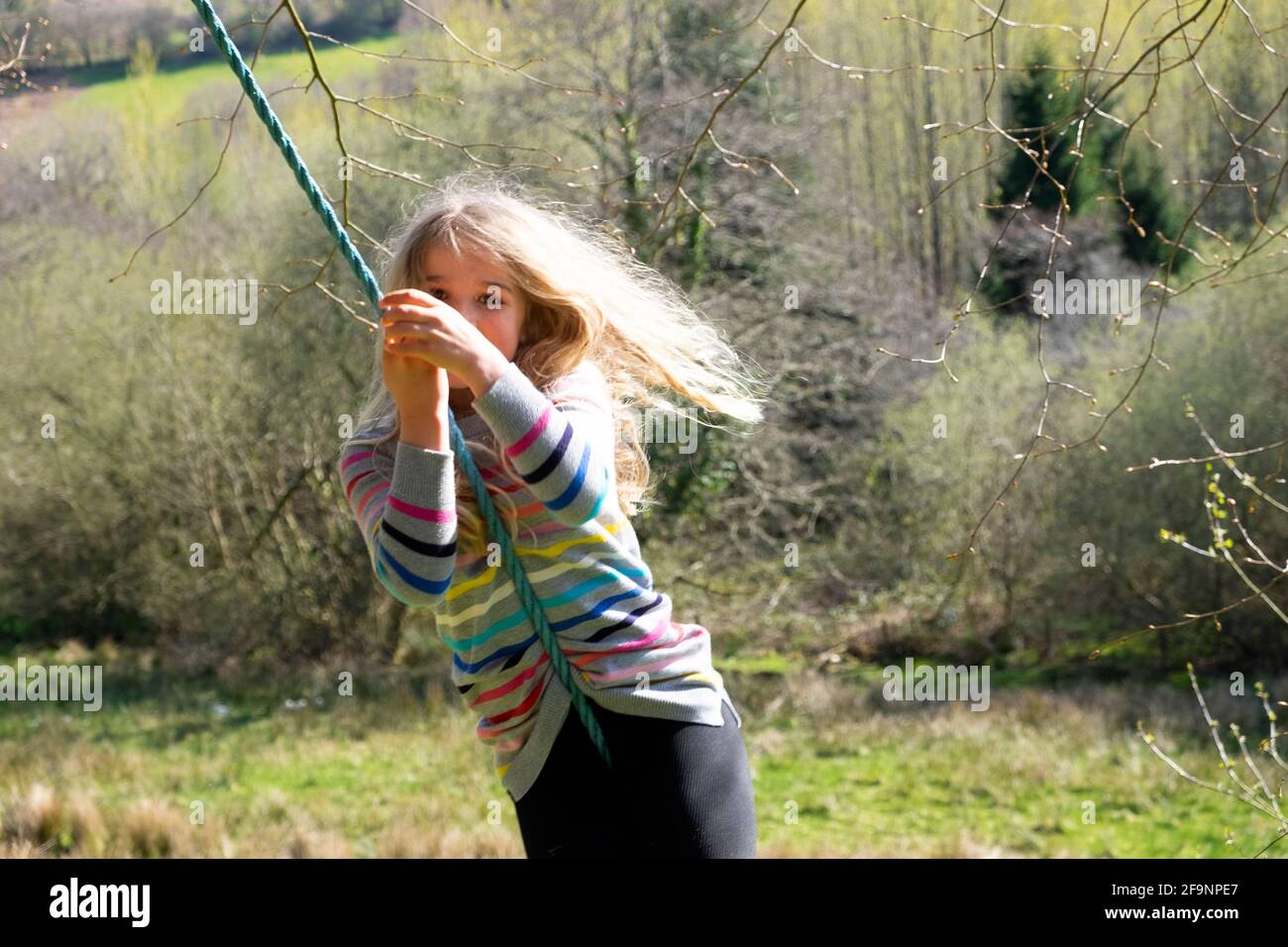 Young girl 8 yrs playing outside on garden  swing in spring in Welsh countryside after easing of Covid 19 lockdown restrictions Wales UK KATHY DEWITT Stock Photo
