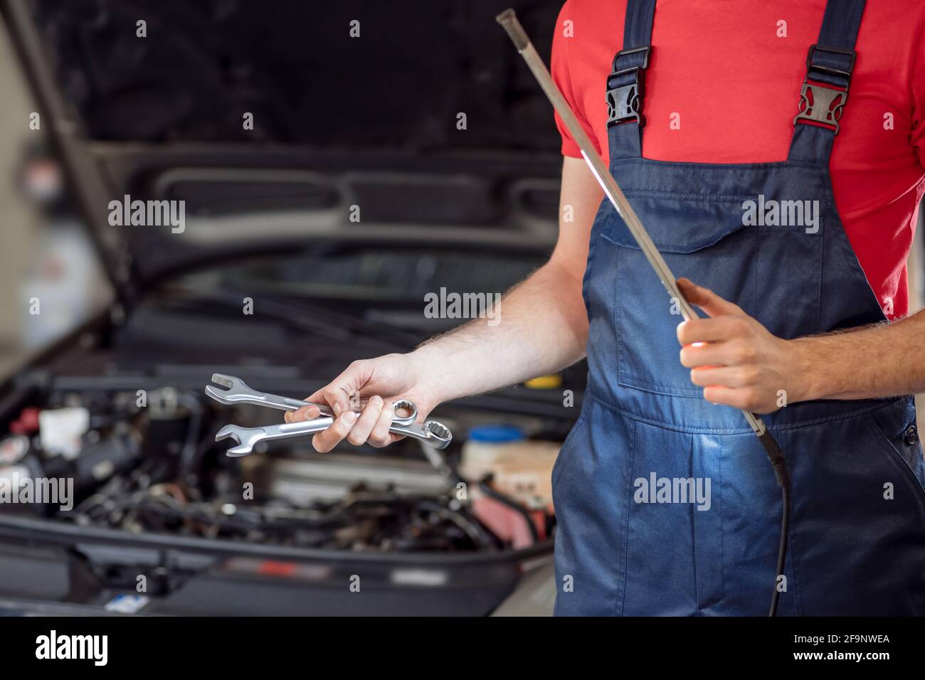 Auto mechanic hands with wrenches and lamp Stock Photo