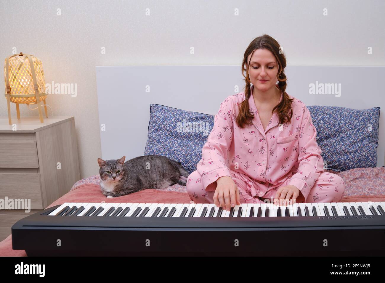 Uma Mulher De Pijama Rosa Está Transmitindo Um Jogo De Piano Online Na  Internet. Pianista Sorridente Mostrando Boas-vindas Com Ges Foto de Stock -  Imagem de quarto, interior: 219052440
